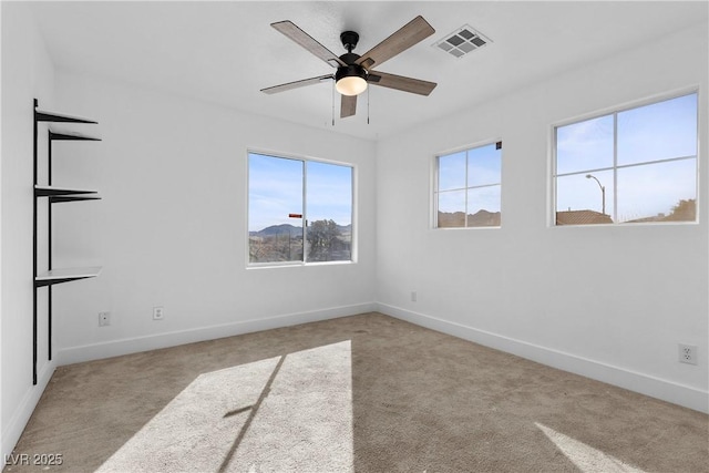 carpeted empty room with baseboards, visible vents, and ceiling fan