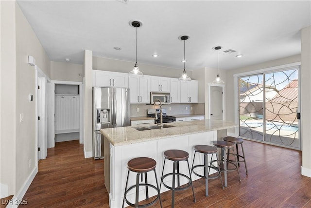 kitchen with tasteful backsplash, dark wood finished floors, an island with sink, stainless steel appliances, and a sink