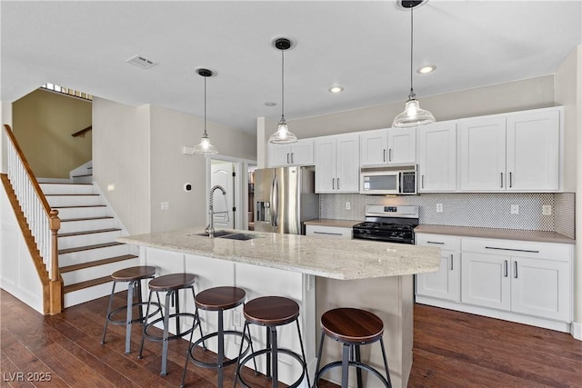 kitchen featuring dark wood-type flooring, a sink, backsplash, white cabinetry, and stainless steel appliances