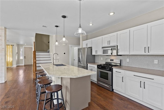 kitchen with tasteful backsplash, a kitchen bar, dark wood-style floors, stainless steel appliances, and a sink