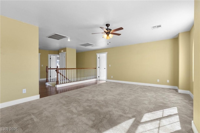 empty room featuring visible vents, ceiling fan, and carpet