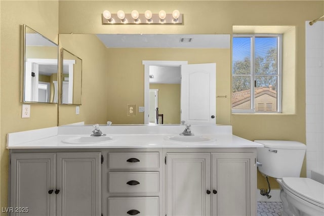 bathroom with a sink, visible vents, toilet, and double vanity