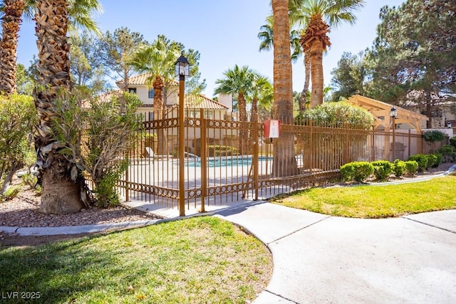 view of gate with a patio area, a yard, fence, and a fenced in pool