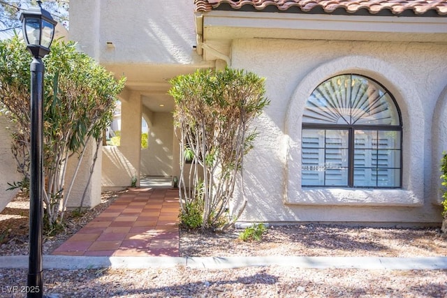 view of side of home with a tile roof and stucco siding