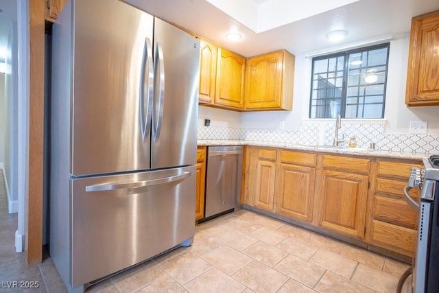 kitchen with tasteful backsplash, brown cabinets, stainless steel appliances, and a sink