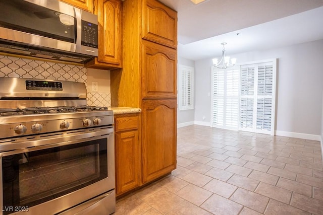 kitchen with brown cabinets, backsplash, appliances with stainless steel finishes, and an inviting chandelier