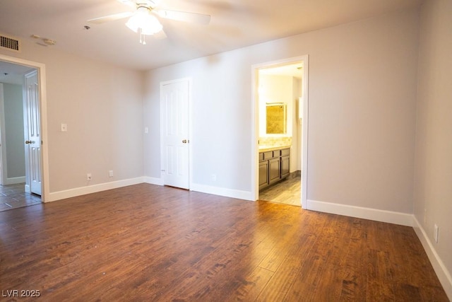 empty room with wood finished floors, a ceiling fan, and baseboards