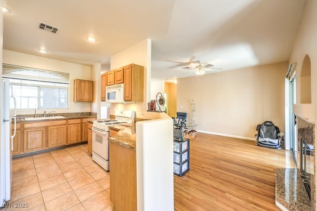 kitchen with white appliances, visible vents, ceiling fan, a sink, and open floor plan