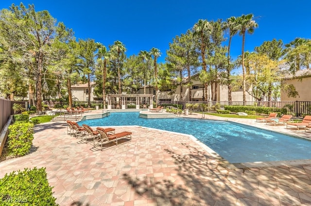 community pool with a patio area and fence