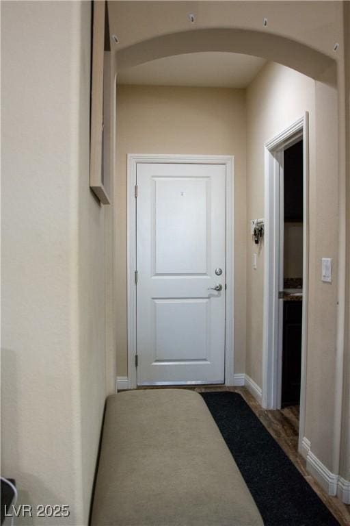 doorway to outside featuring baseboards and arched walkways