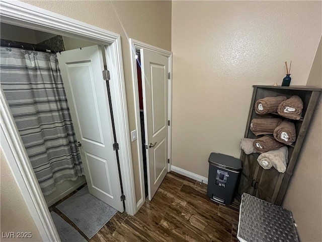 corridor featuring baseboards and dark wood-style flooring