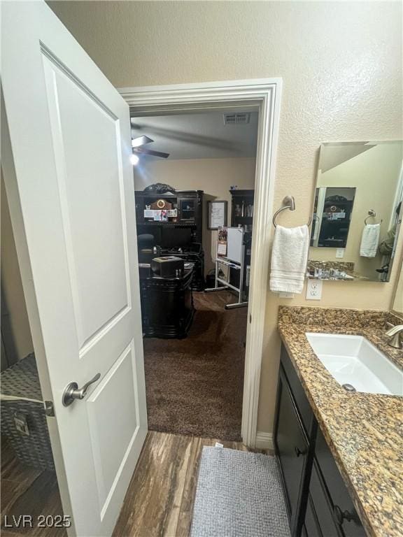 bathroom with visible vents, vanity, a ceiling fan, and wood finished floors