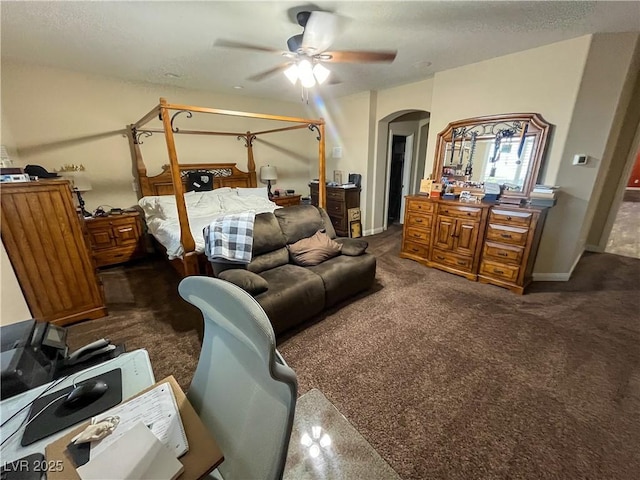 bedroom featuring baseboards, arched walkways, dark colored carpet, and ceiling fan