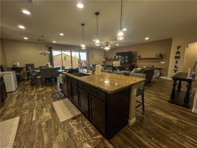 kitchen featuring dark wood-style flooring, a kitchen breakfast bar, ceiling fan, and a sink