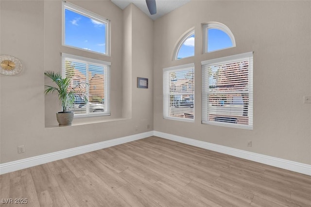 unfurnished room featuring baseboards, plenty of natural light, and wood finished floors