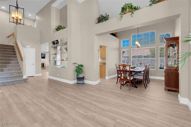 dining space with baseboards, stairs, recessed lighting, light wood-style flooring, and a notable chandelier