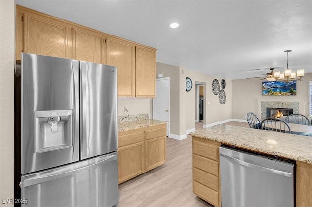 kitchen with light wood-type flooring, stainless steel appliances, light brown cabinetry, and light countertops