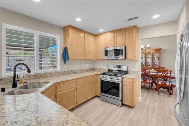 kitchen featuring visible vents, light wood-type flooring, light brown cabinetry, a sink, and appliances with stainless steel finishes