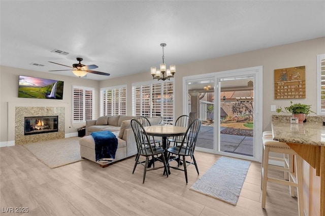 dining space featuring a premium fireplace, visible vents, and light wood-type flooring