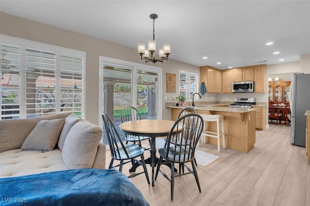 dining area with recessed lighting, a notable chandelier, and light wood-style flooring