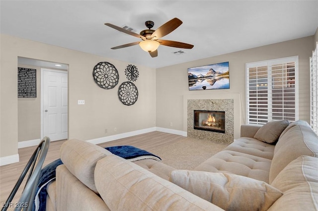 living area with visible vents, baseboards, light wood-type flooring, and a ceiling fan