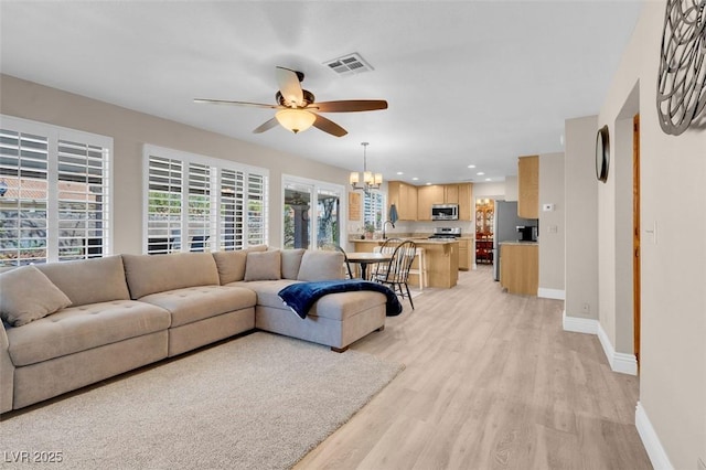 living room with visible vents, baseboards, light wood-style flooring, recessed lighting, and ceiling fan with notable chandelier