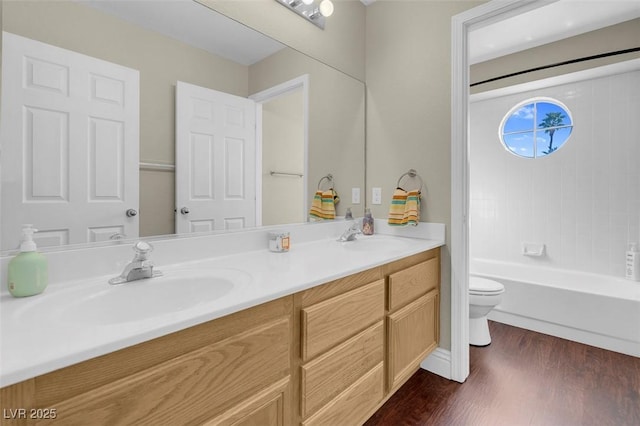 bathroom featuring double vanity, a sink, toilet, and wood finished floors