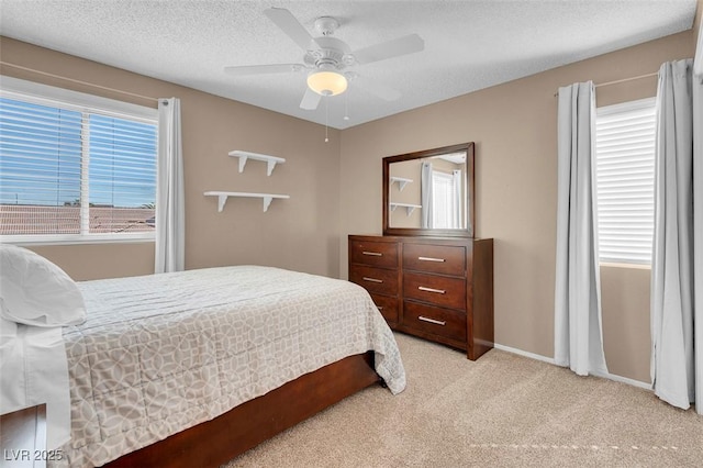 bedroom with light colored carpet, a textured ceiling, baseboards, and ceiling fan