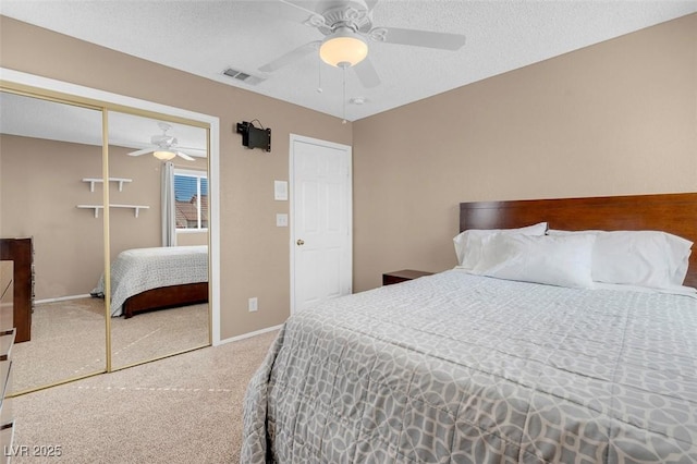 carpeted bedroom featuring visible vents, a textured ceiling, a closet, baseboards, and ceiling fan