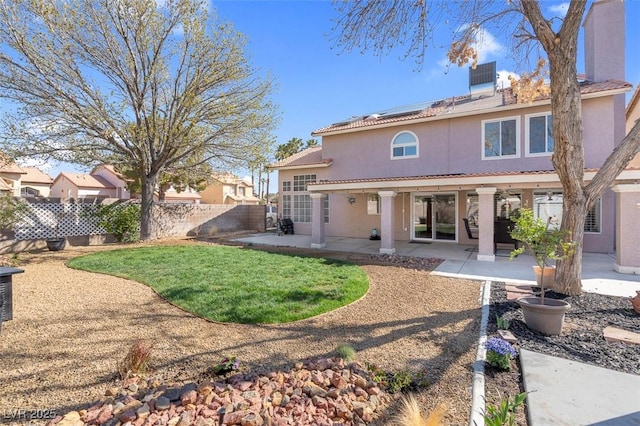 back of property with roof mounted solar panels, a patio area, a fenced backyard, and stucco siding