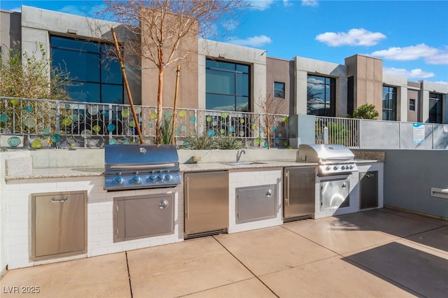 view of patio / terrace with an outdoor kitchen, a sink, fence, and grilling area