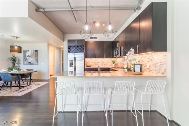 kitchen with tasteful backsplash, visible vents, appliances with stainless steel finishes, a peninsula, and dark wood-style floors