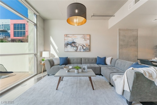 living area featuring a wall of windows, visible vents, and wood finished floors