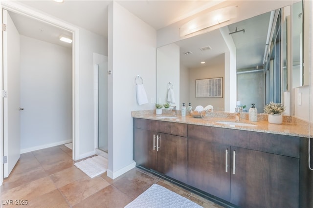 bathroom with a shower stall, double vanity, baseboards, and a sink