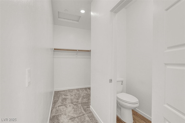 bathroom with baseboards, toilet, and a walk in closet