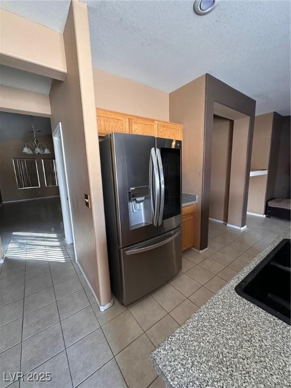 kitchen with light tile patterned floors, stainless steel fridge, a textured ceiling, and a sink