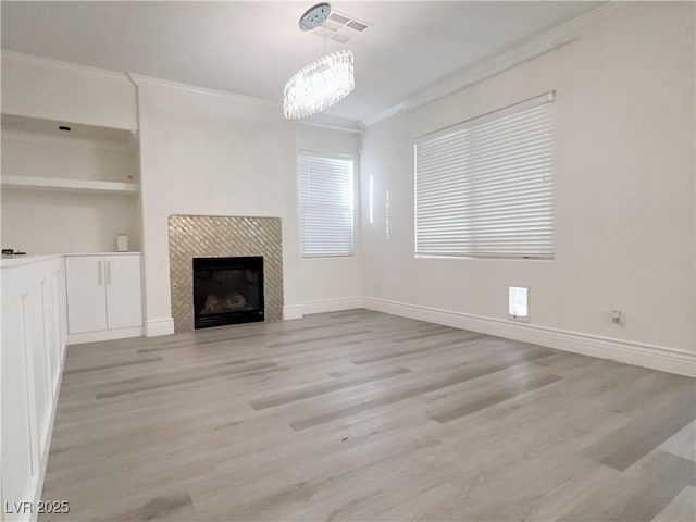 unfurnished living room with light wood-style flooring, a fireplace, baseboards, and ornamental molding