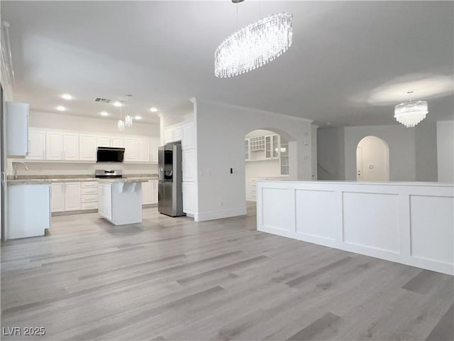 kitchen with arched walkways, stainless steel appliances, open floor plan, a chandelier, and a center island