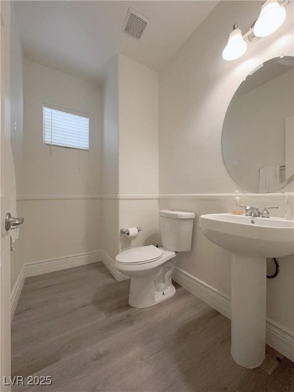 bathroom with visible vents, toilet, baseboards, and wood finished floors