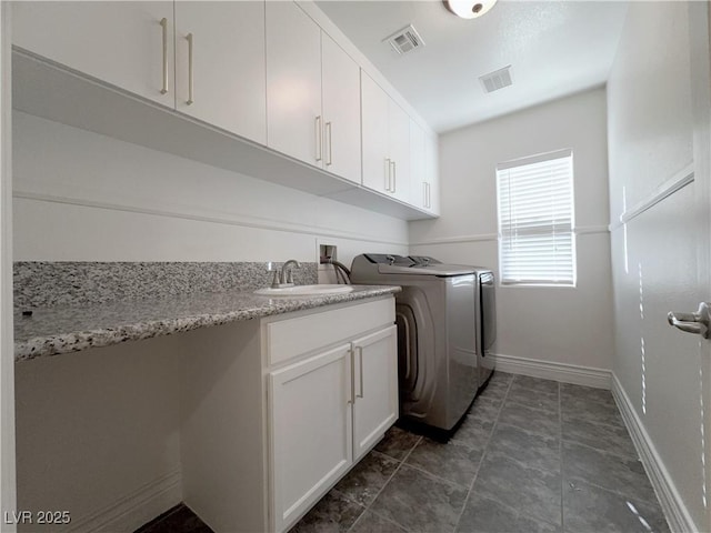 clothes washing area featuring a sink, visible vents, cabinet space, and washing machine and dryer