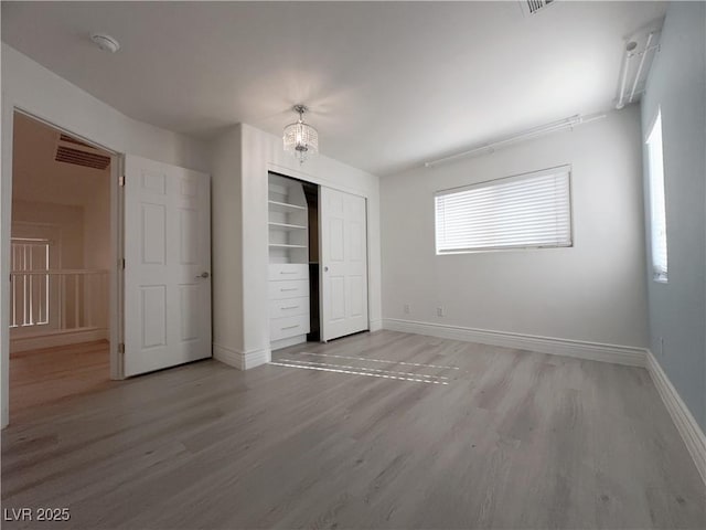 unfurnished bedroom featuring a closet, baseboards, and light wood finished floors