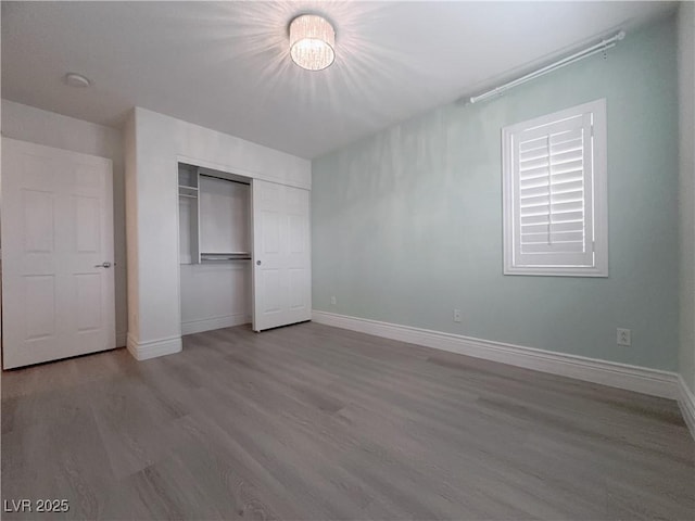 unfurnished bedroom featuring a closet, baseboards, and wood finished floors