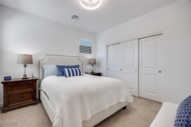 bedroom with a closet, visible vents, and light colored carpet