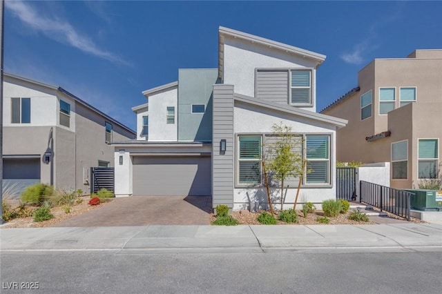 contemporary home with central AC unit, an attached garage, decorative driveway, and stucco siding