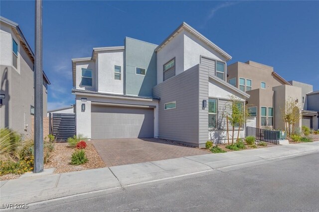 modern home with an attached garage, decorative driveway, and stucco siding