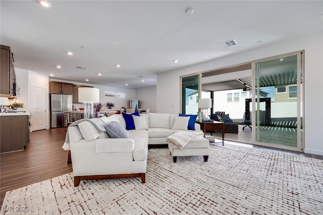 living room featuring visible vents, light wood-style flooring, and recessed lighting