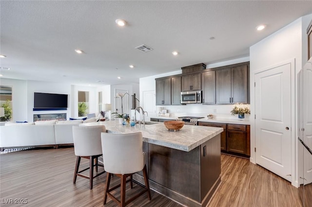 kitchen with visible vents, a sink, light countertops, appliances with stainless steel finishes, and a kitchen breakfast bar
