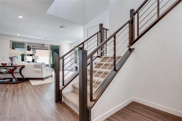 staircase featuring wood finished floors, baseboards, visible vents, and recessed lighting