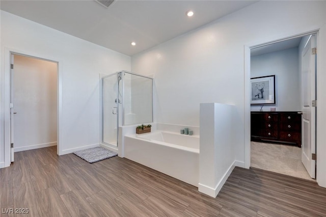 full bathroom featuring a bath, a stall shower, wood finished floors, and recessed lighting