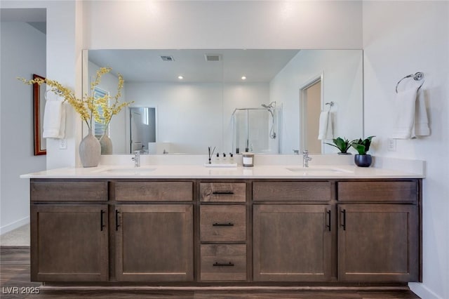 full bath featuring a shower stall, double vanity, visible vents, and a sink